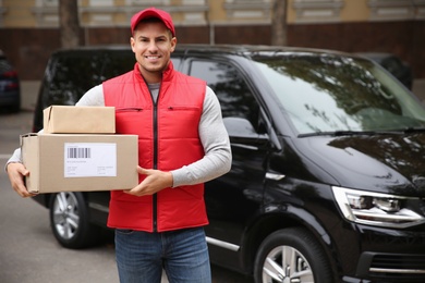 Courier with parcels near delivery van outdoors