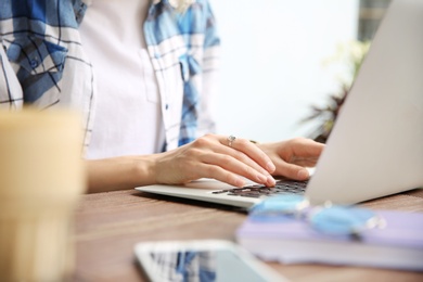 Photo of Young woman working with laptop at desk, closeup