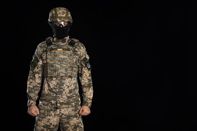 Soldier in Ukrainian military uniform, tactical goggles and balaclava on black background. Space for text