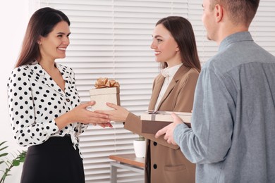 Woman and man presenting gift boxes to colleague in office