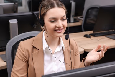 Photo of Young call center operator with headset working in modern office
