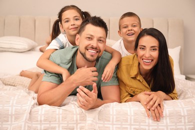 Portrait of happy family with children on bed at home