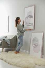 Woman hanging picture on wall in room. Interior design