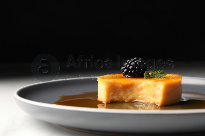 Delicious pudding with caramel and blackberry on plate, closeup