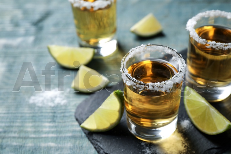 Mexican Tequila shots, lime slices and salt on blue wooden table
