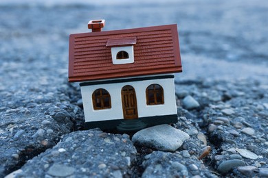 House model in cracked asphalt. Earthquake disaster