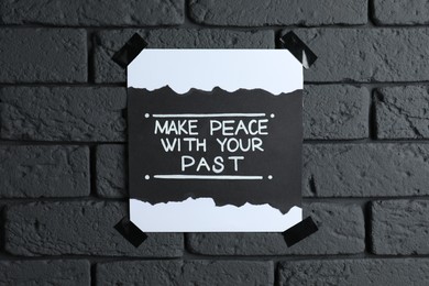 Card with life-affirming phrase Make Peace With Your Past on dark brick wall