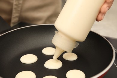 Woman cooking cereal pancake on frying pan, closeup