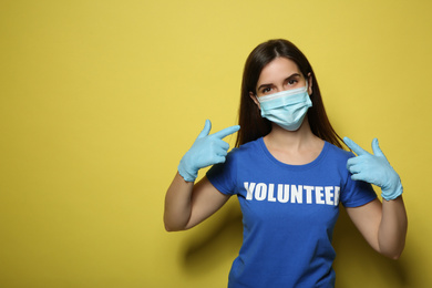 Female volunteer in mask and gloves on yellow background, space for text. Protective measures during coronavirus quarantine