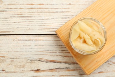 Photo of Pickled ginger in bowl on white wooden table, top view. Space for text