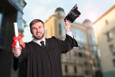 Happy student with graduation hat and diploma outdoors