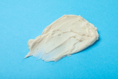 Smear of delicious cream cheese on light blue background, top view
