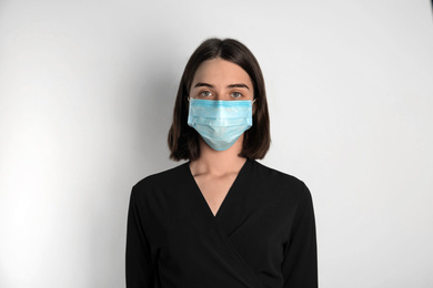 Woman with disposable mask on face against white background