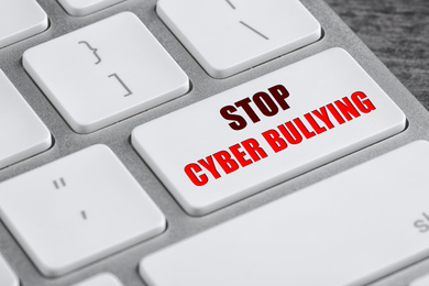 Modern computer keyboard with phrase STOP CYBER BULLYING on white button, closeup