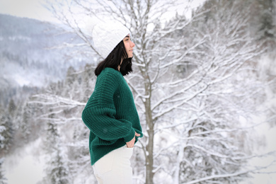 Pretty woman wearing warm sweater in winter forest