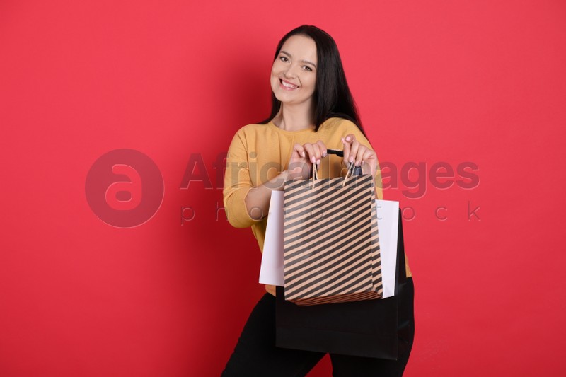 Beautiful overweight woman with shopping bags on red background