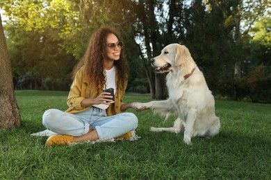 Young African-American woman and her Golden Retriever dog on green grass in park