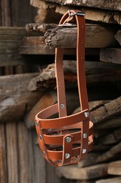 Photo of New brown dog muzzle hanging near firewood