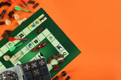 Different types of board games and its' components on orange background, flat lay. Space for text