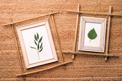 Bamboo frames with green leaves on wicker straw background, flat lay