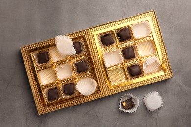 Photo of Partially empty box of chocolate candies on grey background, top view