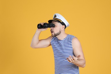 Sailor looking through binoculars on yellow background
