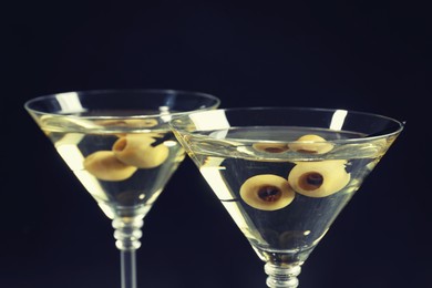 Martini cocktails with olives on dark background, closeup