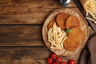 Delicious fried breaded cutlets served on wooden table, flat lay. Space for text