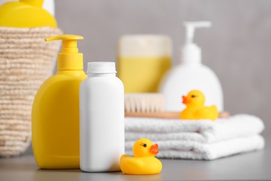 Photo of Baby cosmetic products, towel and rubber ducks on grey table, space for text