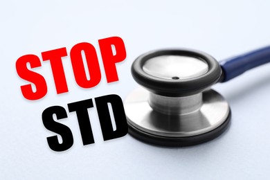 Text STOP STD and stethoscope on light background, closeup