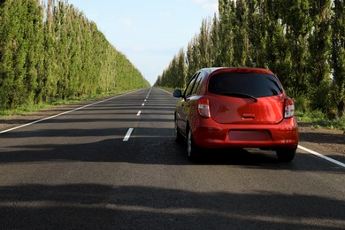 Red car on asphalt road in countryside