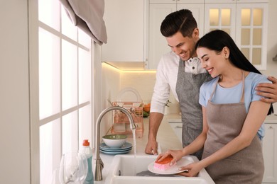 Happy lovely couple washing dishes in kitchen