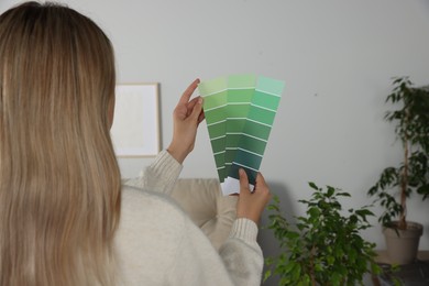 Woman with paint chips choosing color for wall in room. Interior design
