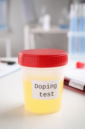 Jar with urine sample on white table indoors. Doping control