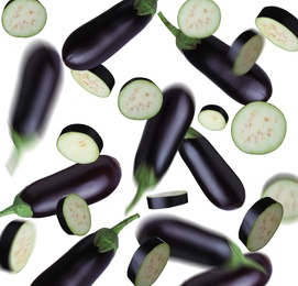 Cut and whole eggplants falling on white background