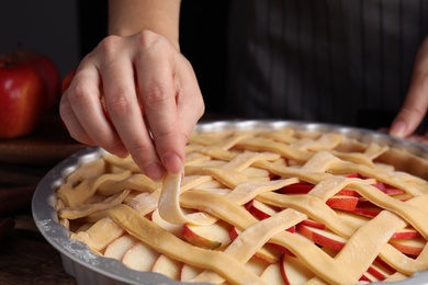 Woman making lattice top for traditional English apple pie, closeup