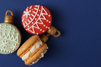 Photo of Beautifully decorated Christmas macarons on blue background, flat lay. Space for text