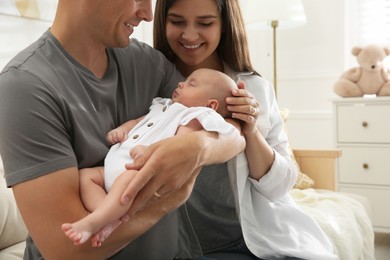 Happy couple holding their sleeping baby at home, closeup