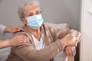 Doctor taking care of lonely senior woman in protective mask at nursing home