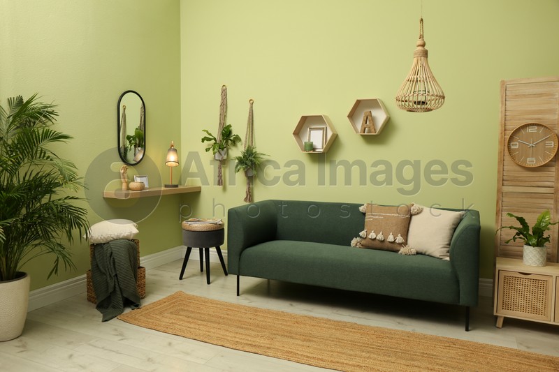 Photo of Living room with comfortable green sofa. Interior design