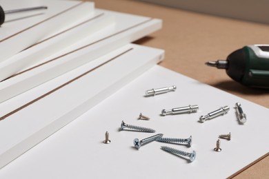 White furniture assembly parts and different metal fasteners on brown background