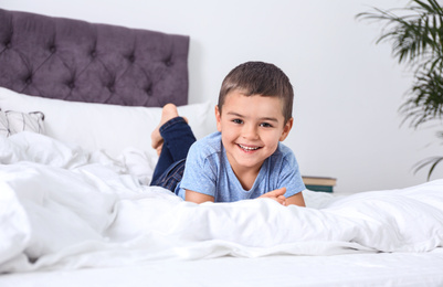 Cute little boy lying on bed at home
