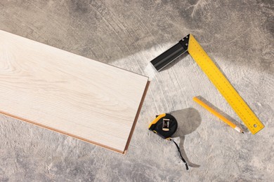 Photo of Parquet plank, measuring tape, pencil and ruler on floor, flat lay