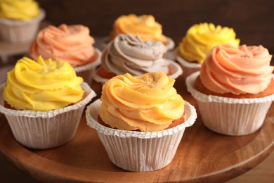 Photo of Tasty cupcakes with cream on wooden stand, closeup