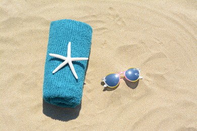Photo of Towel with stylish sunglasses and starfish on sand outdoors, flat lay. Beach accessories