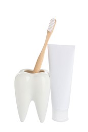 Tooth shaped holder with brush near tube of toothpaste on white background