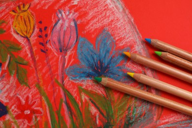 Colorful pastel pencils on beautiful painting, flat lay