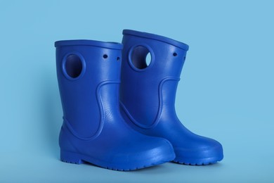 Pair of bright rubber boots on light blue background