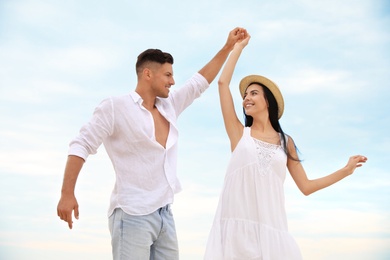 Happy young couple dancing outdoors in summer