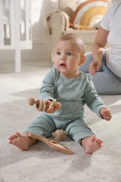Cute baby girl playing with wooden toys and mother on floor at home
